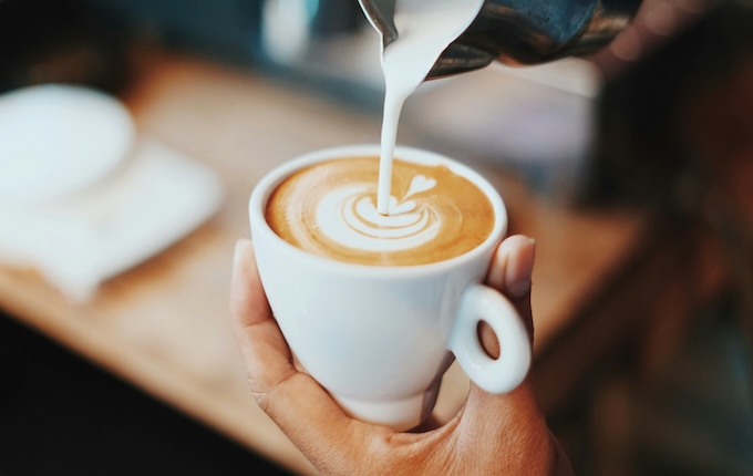 Milch in eine Kaffeetasse gießen