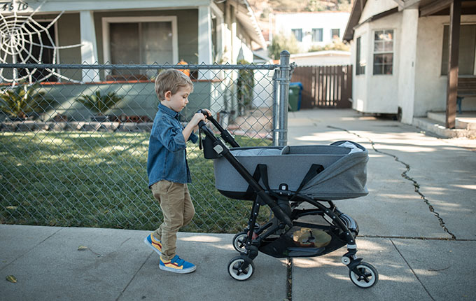 Kind schiebt Kinderwagen