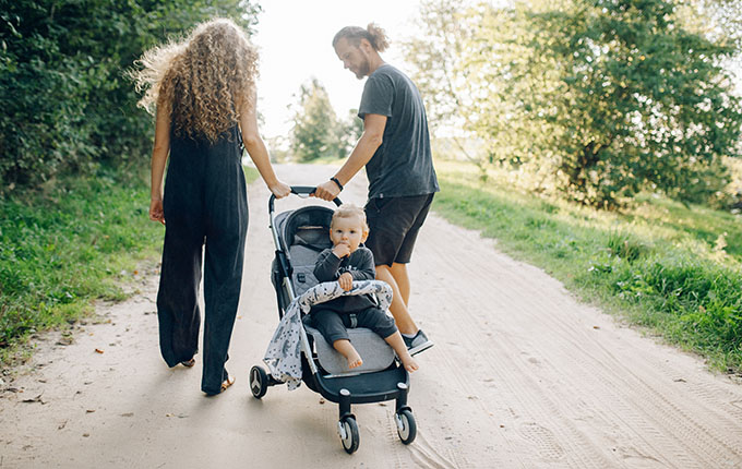 Eltern gehen mit Kinderwagen spazieren