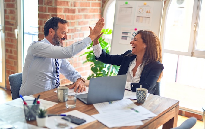 Two people high fiving at work