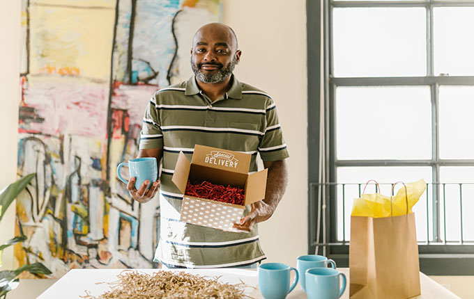 Bir karton kutu içinde bir kupa paketleyen adam